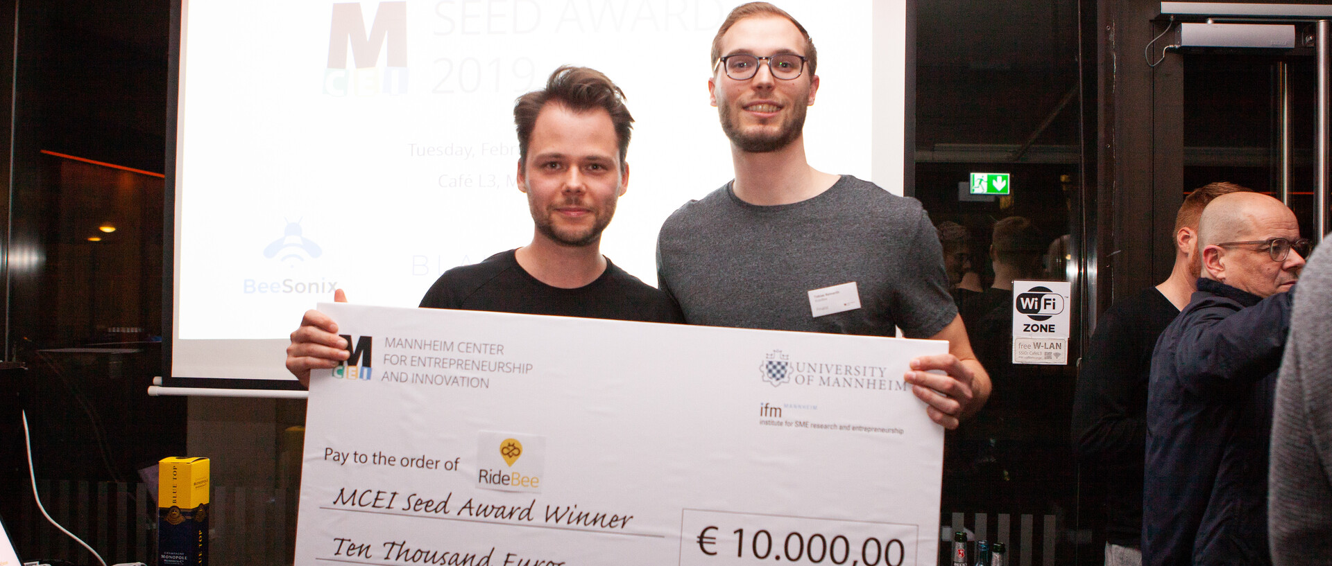 Zwei junge Männer mit einem gewonnenen Scheck über 10.000 Euro