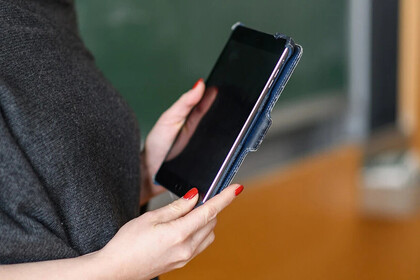 Seitenansicht auf eine Person, die ein IPad in den Händen hält. Das Gesicht oder der Körper abwärts der Hüfte sind nicht zu sehen.