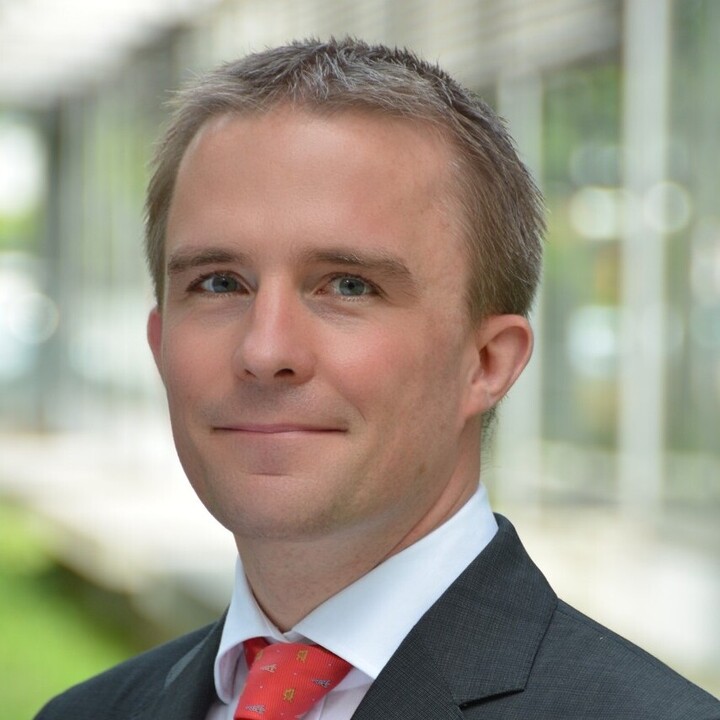 Portrait eines Mannes in Anzug und roter Krawatte.