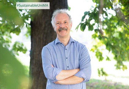 Prof. Dr. Moritz Fleischmann. Er lächelt, sein Hemd ist hellblau gestreift und er hat einen Schnurrbart.