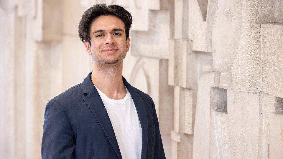 Porträt von Virgil Baclanoc. Er steht vor einer Wand, hat schwarze kurze Haare und trägt ein dunkelblaues Jackett.