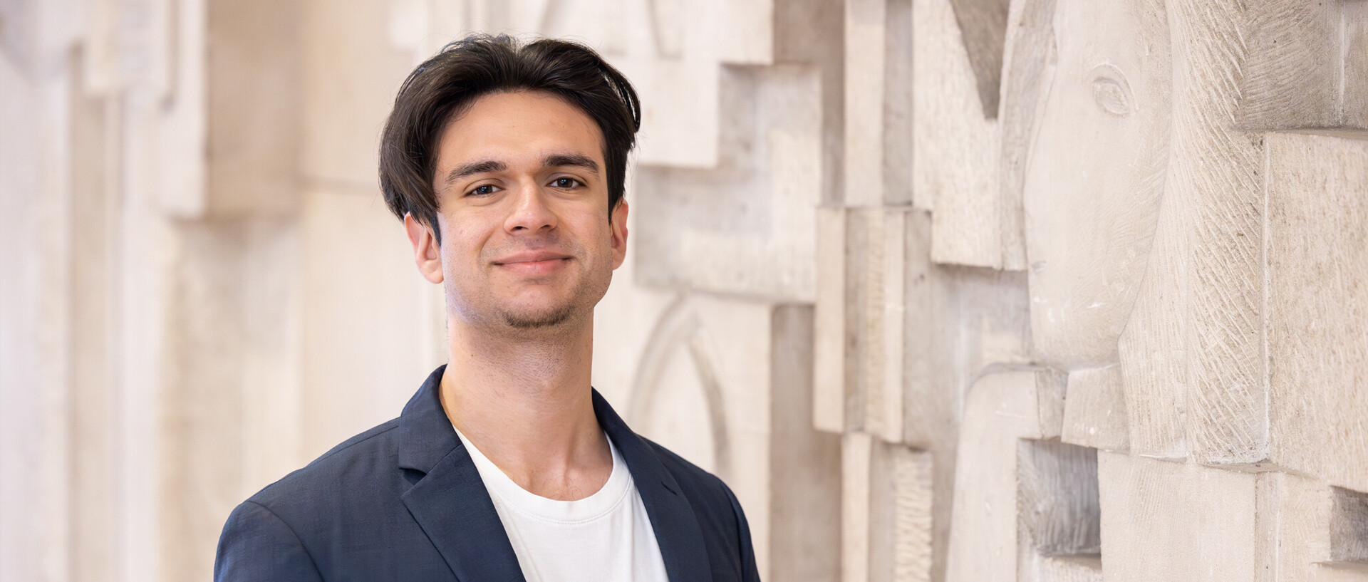 Porträt von Virgil Baclanoc. Er steht vor einer Wand, hat schwarze kurze Haare und trägt ein dunkelblaues Jackett.