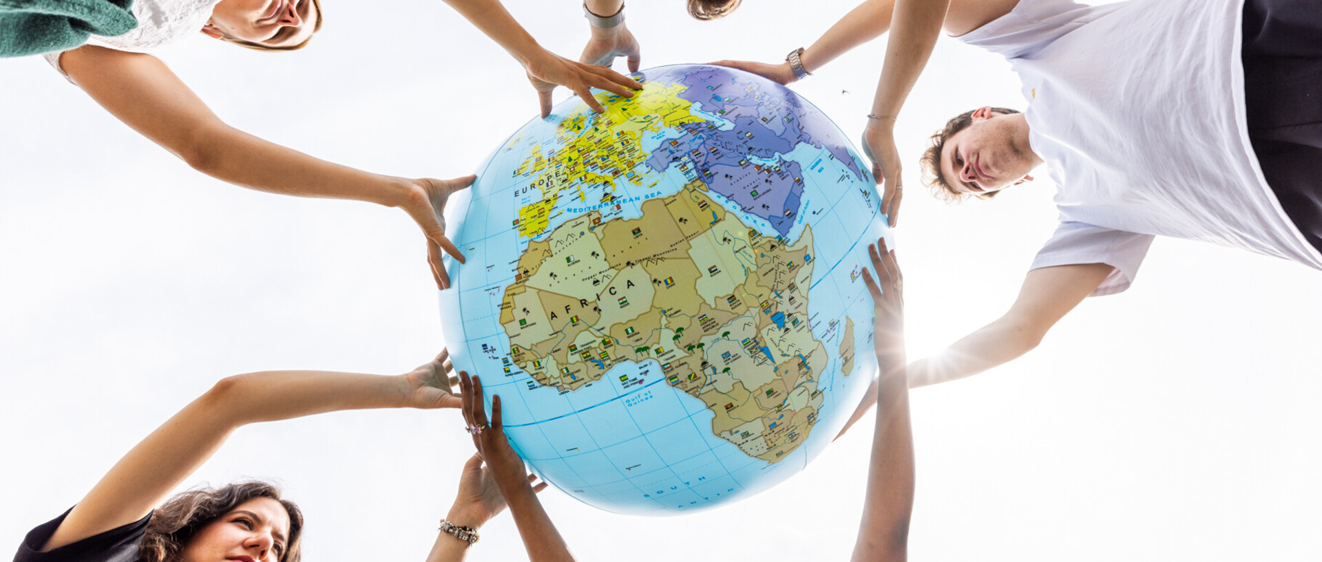 Fünf Studierende halten zusammen einen großen Globus in den Händen. Der Fokus des Globus liegt auf Africa.