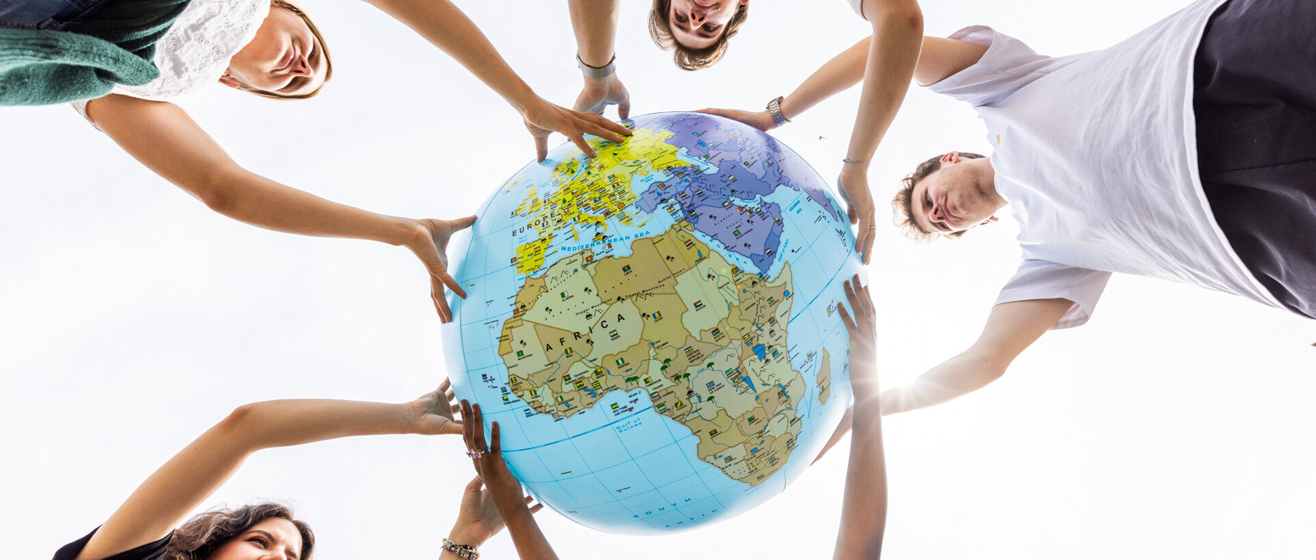 Fünf Studierende halten zusammen einen großen Globus in den Händen. Der Fokus des Globus liegt auf Africa.