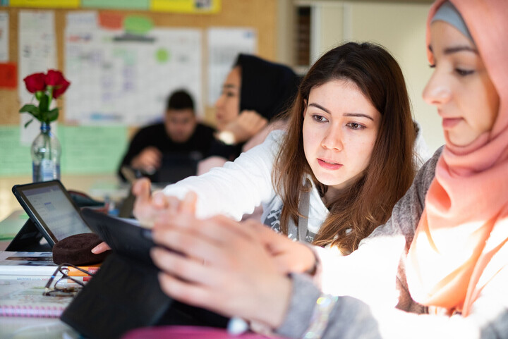Zwei Studentinnen schauen gemeinsam in ein Tablet. 