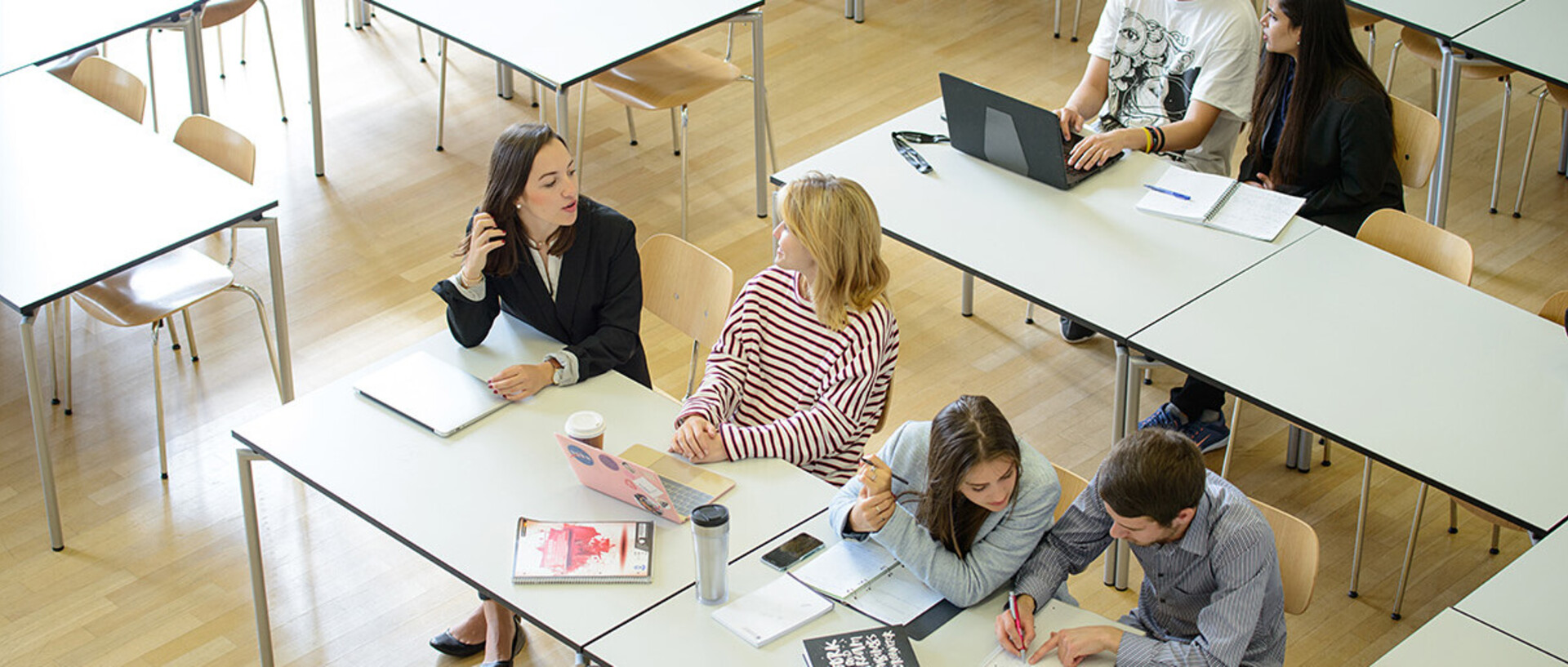 Seminar room at the University of Mannheim. Students sit at tables and go through their tasks together.