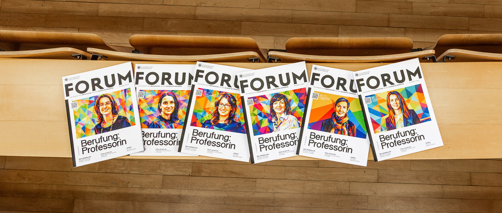 Sechs FORUM-Exemplare liegen nebeneinander auf einem Tisch in einem Hörsaal.