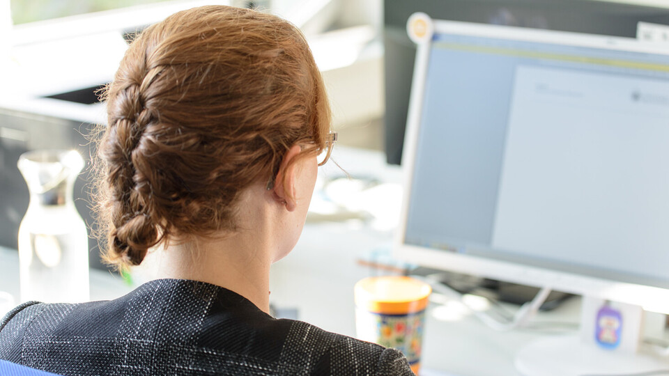 Eine Frau sitzt vor einem Computer.