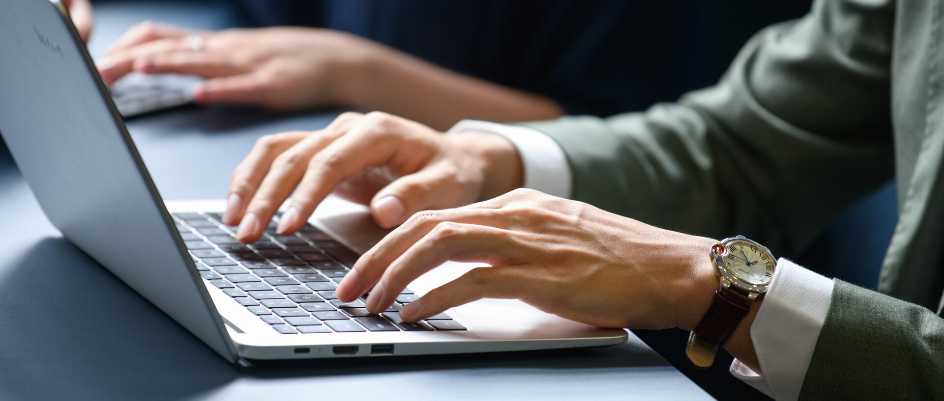 Man in a suit working on a laptop. View of the hands and the open laptop