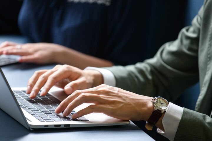 Mann im Anzug, der am Laptop arbeitet. Blick auf die Hände und das offene Laptop