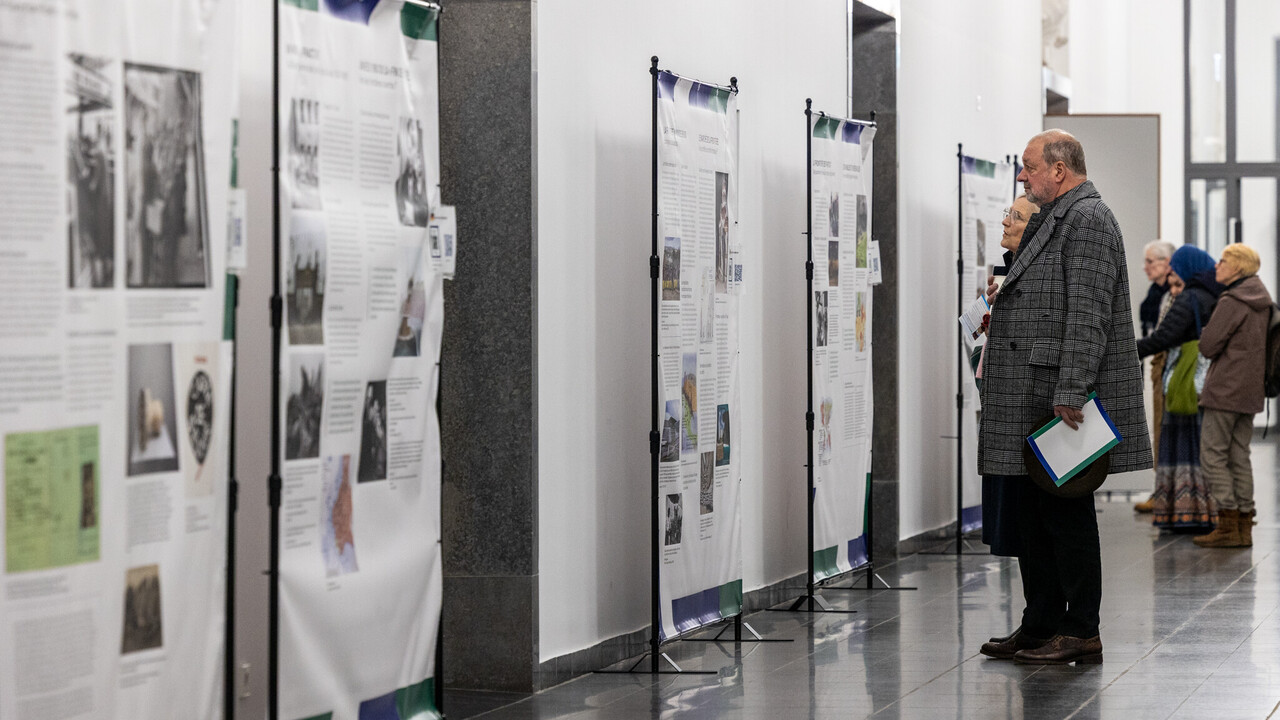 Mehrere Personen lesen Ausstellungstafeln bei einer Vernissage