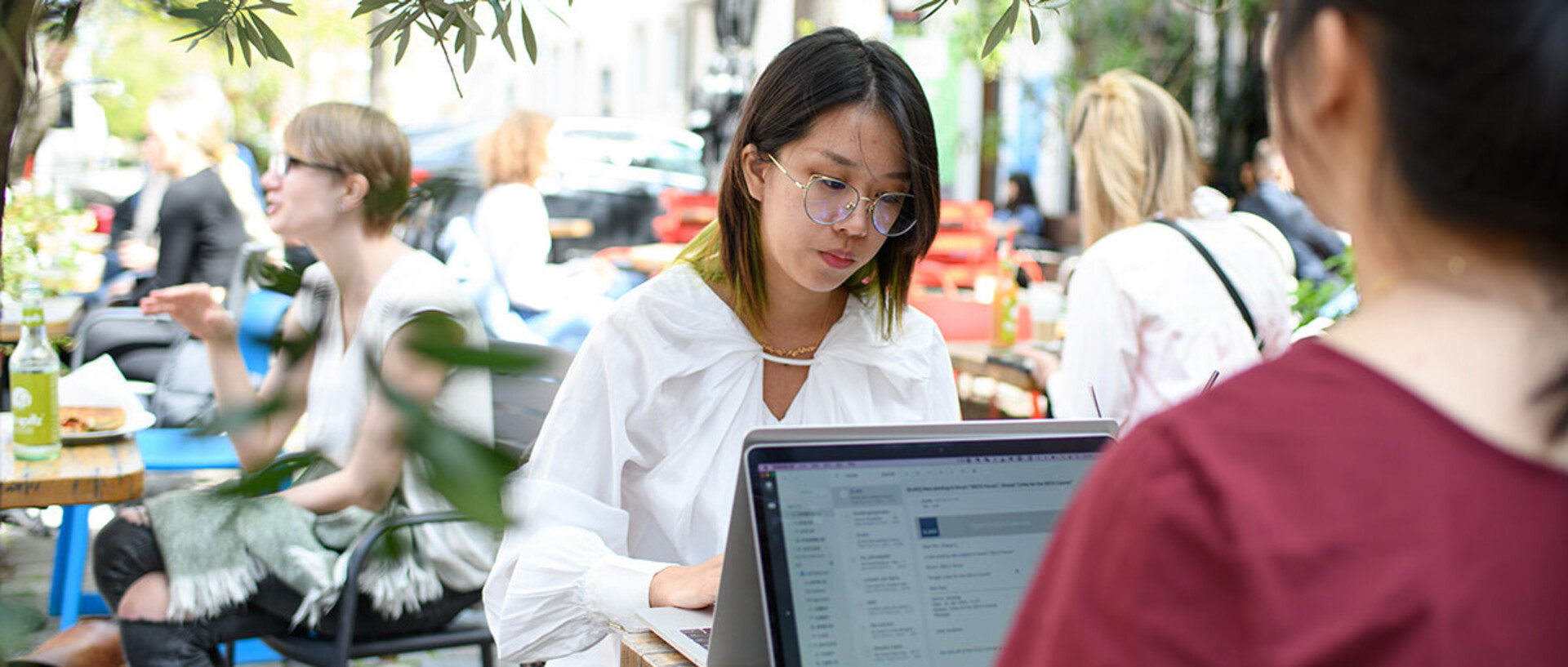 Two people working on their laptops in the outside space of a café