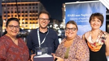 One man and three woman are standing in front of a building at night.