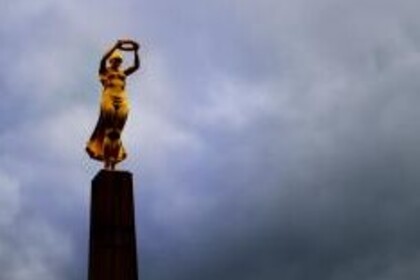 Eine Frau in gelbem Gewand steht auf einem Turm und hält einen Ring in die Höhe.