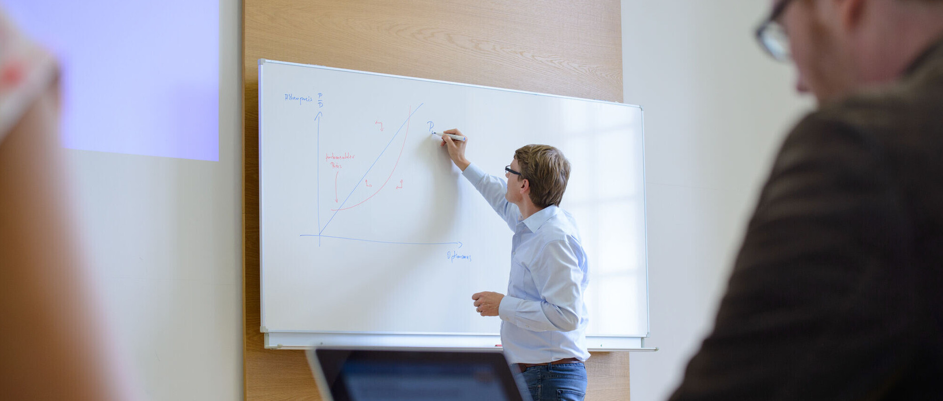 Ein Mann schreibt etwas auf ein Whiteboard.