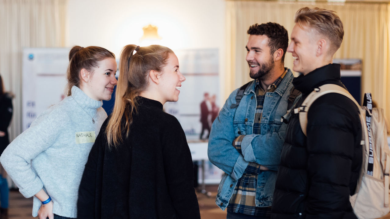 Vier Studierende stehen lachend im Kreis.