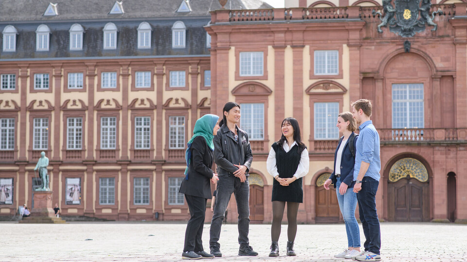 Fünf Persone stehen auf dem Ehrenhof des Schlosses und reden miteinander.