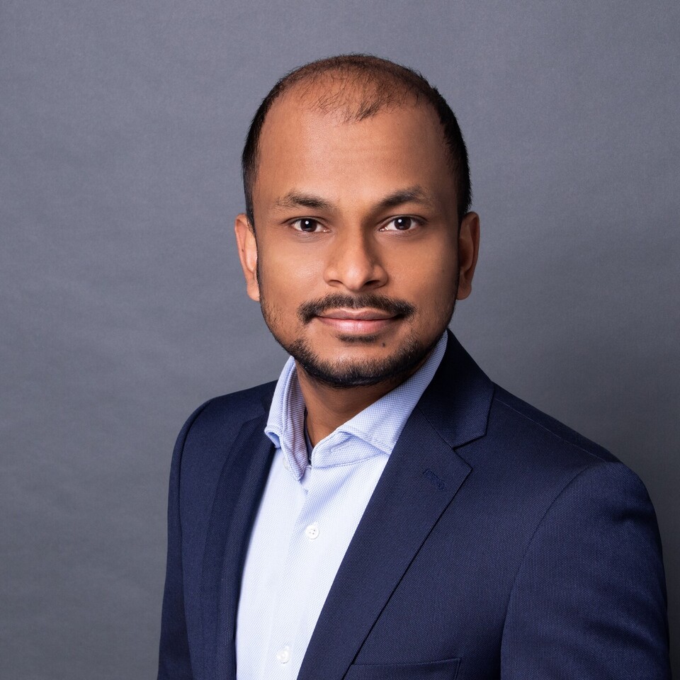 Santanu Kundu in einem hellblauen Hemd und dunklem Blazer vor einem grauen Fotohintergrund.