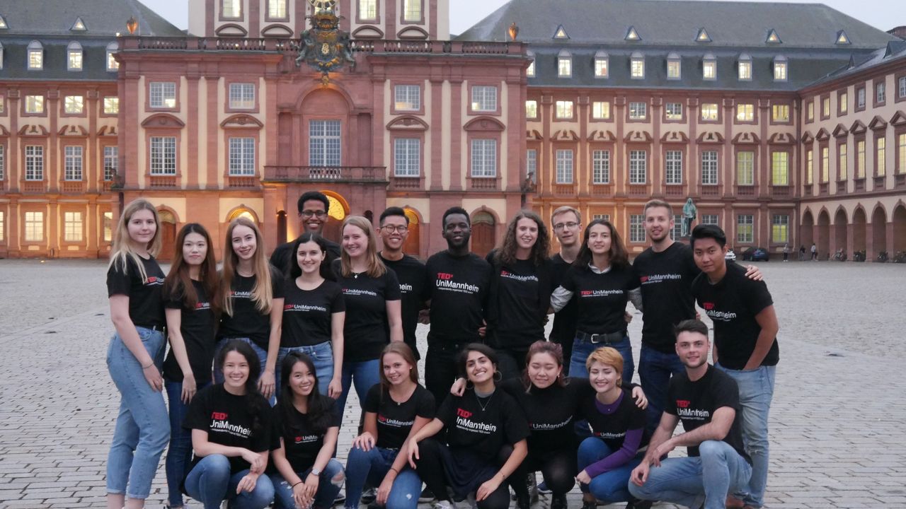 Eine Gruppe von Studierenden posiert vor dem Mannheimer Schloss. Sie tragen alle ein schwarzes T-Shirt mit der Aufschrit "Tedx UniMannheim".