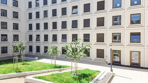 The courtyard of Building B6, 30-32 on campus with trees and banks.