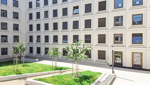 The courtyard of Building B6, 30-32 on campus with trees and banks.