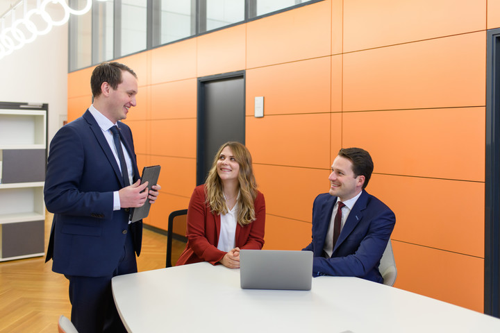 3 Personen an einem großen Tisch, die sich unterhalten