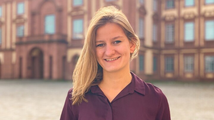 Christin Schmidt. She is wearing a purple shirt and is standing on the Ehrenhof.