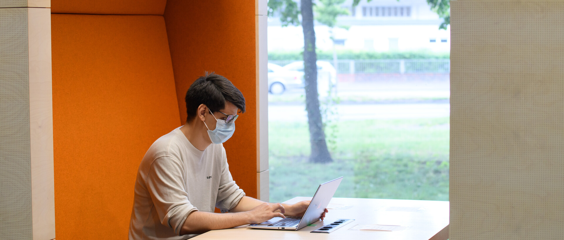 Symbolbild der Coronamaßnahmen. Person, die mit Maske am Laptop arbeitet