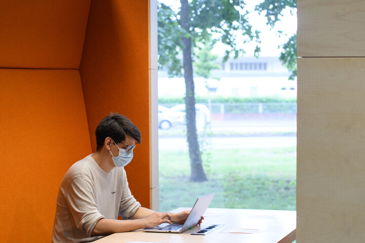 Symbolbild der Coronamaßnahmen. Person, die mit Maske am Laptop arbeitet