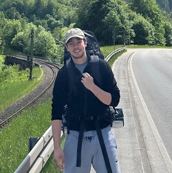 Ein Foto von Marius Goedert mit Rucksack neben einer Eisenbahnschiene