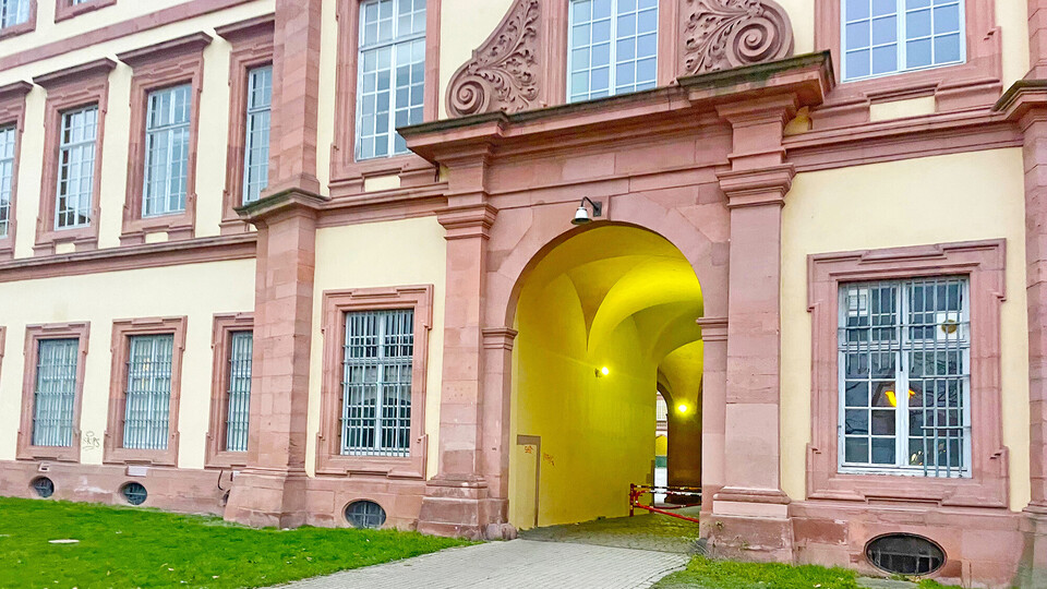 Durchgang des Universitätsgebäudes Ehrenhof-West. Zu sehen ist ein Ausschnitt des Mannheimer Schlosses mit einem Torbogen, durch den man auf die andere Seite des Gebäudes gelangt.