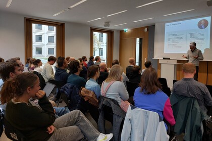 Foto des Academic Speed Dating mit gutgefüllten Stuhlreihen und einem Speaker vorne