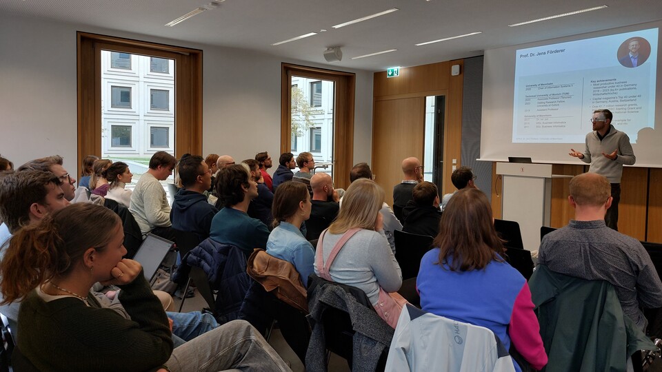 Foto des Academic Speed Dating mit gutgefüllten Stuhlreihen und einem Speaker vorne