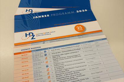 Auf einem Schreibtisch lieger der Papierflyer des Jahresprogramms 2026 des HDZ Baden-Württemberg, aufgeschlagen sind die Angebote der Universität Mannheim