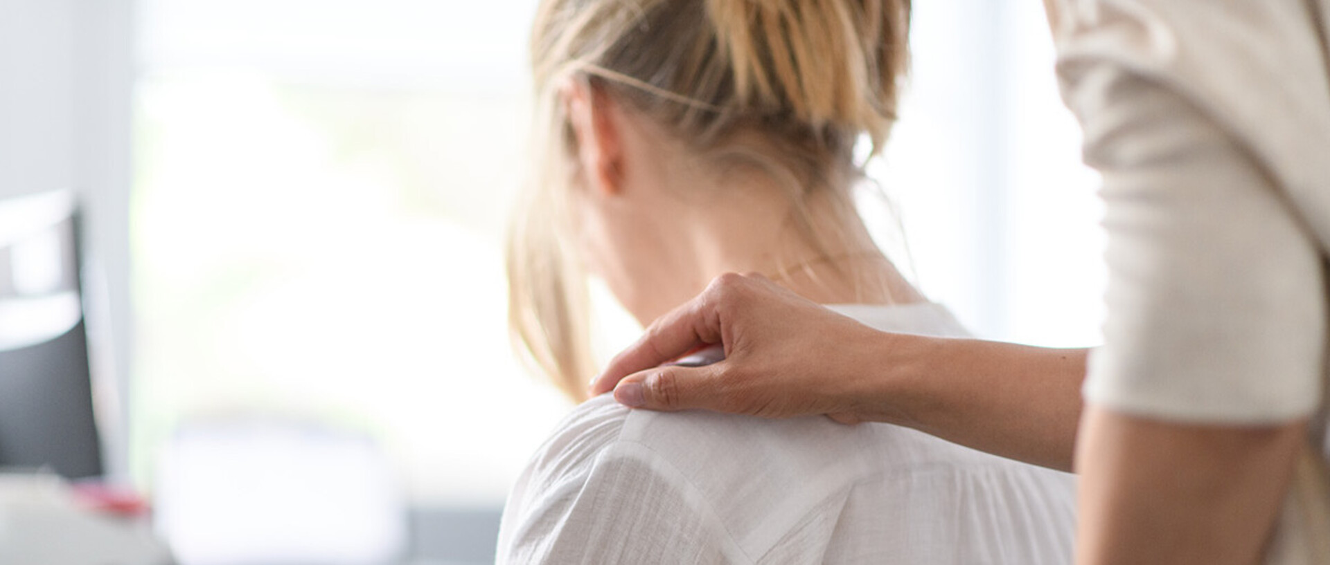 A person compassionately turns to a weary woman at her desk.