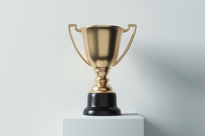 Goldener Pokal auf einem weißen Sockel vor einer weißen Wand.