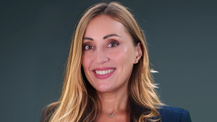 Salam Sami hat lange blonde Haare. Sie trägt ein helles Oberteil und einen dunkelblauen Blazer.