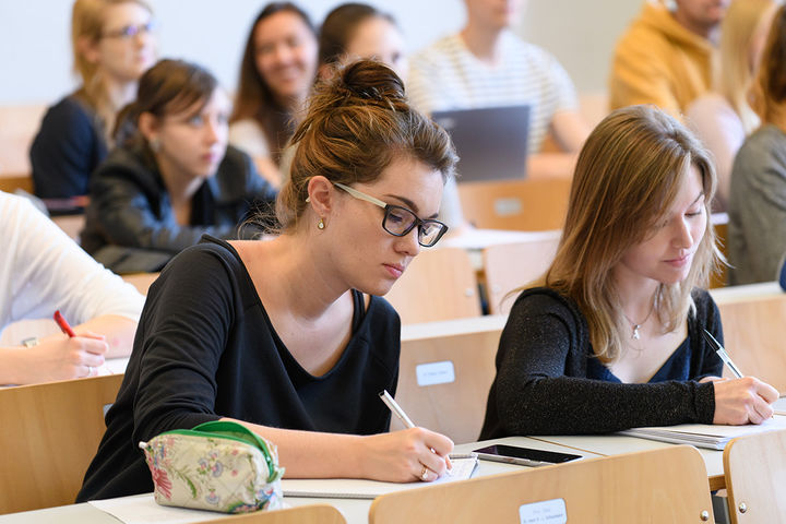 Studentinnen schreiben bei einer Vorlesung mit.