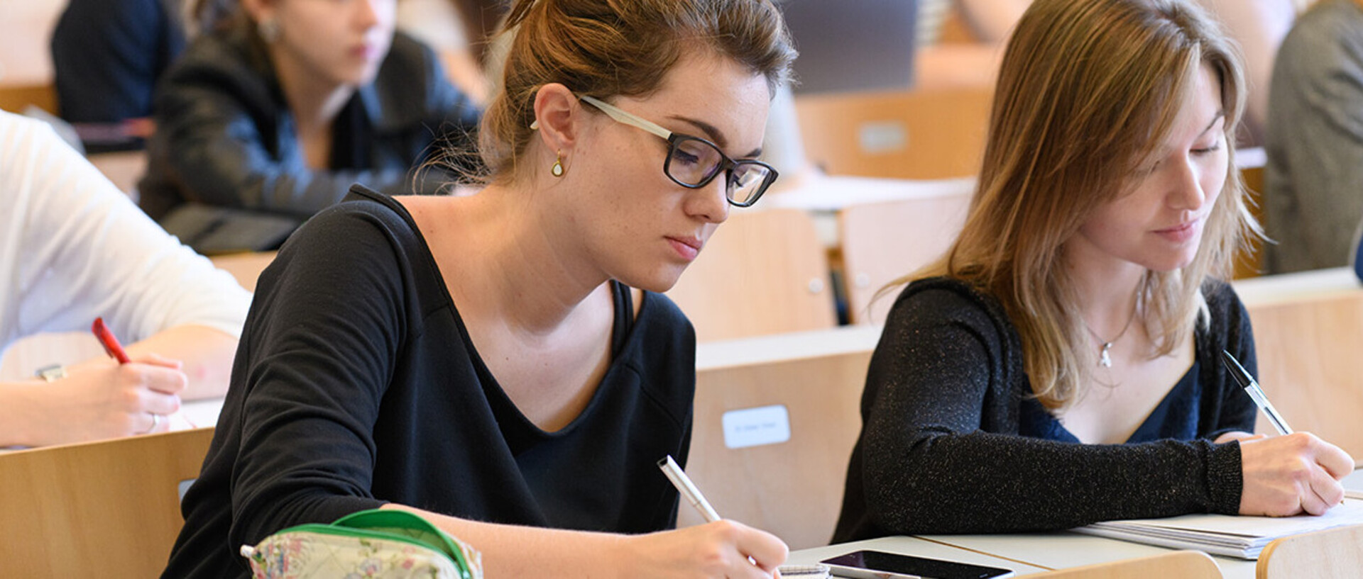Studentinnen schreiben bei einer Vorlesung mit.
