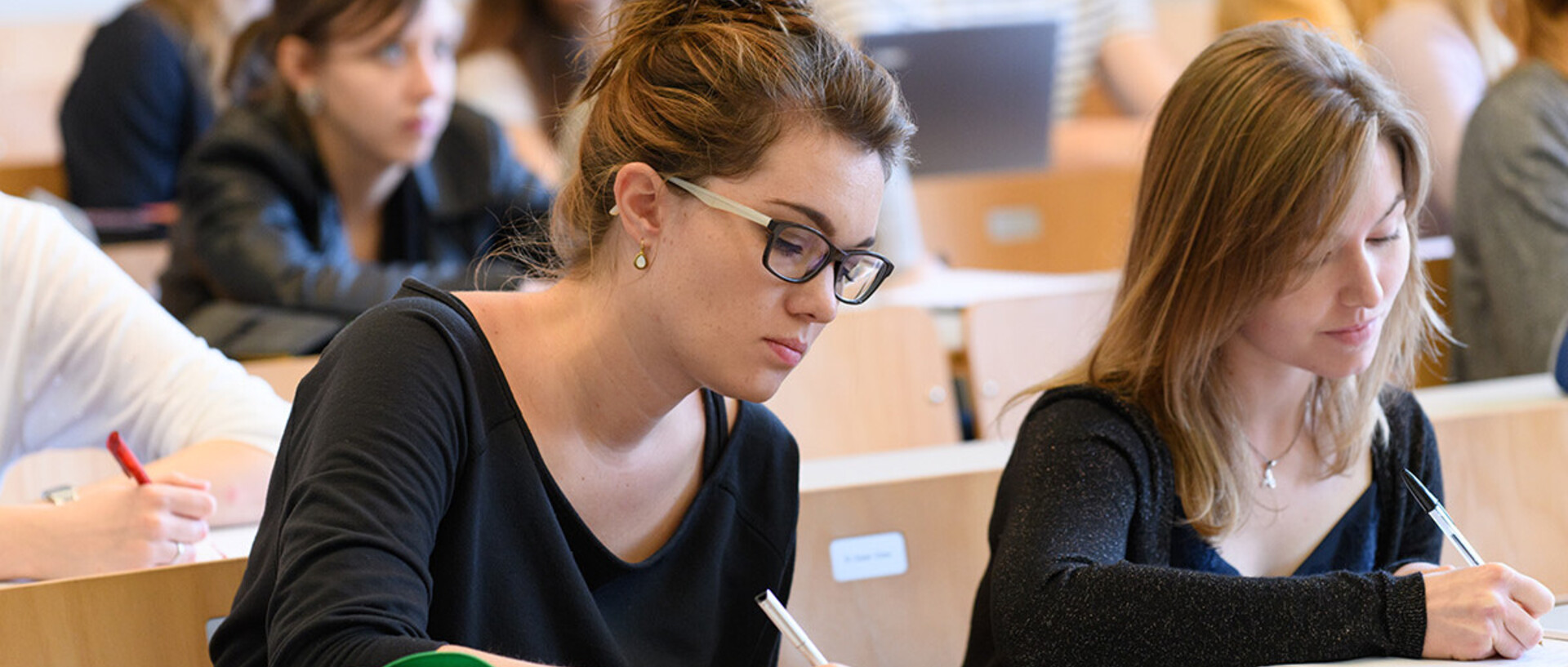 Studentinnen schreiben bei einer Vorlesung mit.