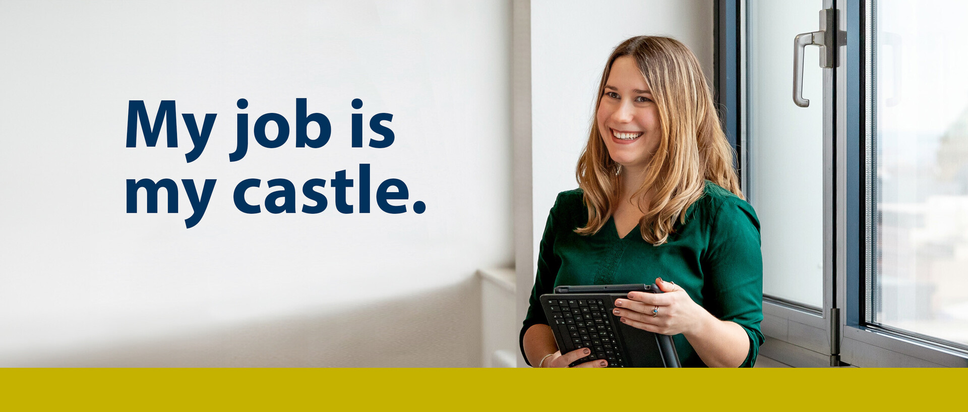Foto mit Text. Eine junge Frau mit braunen langen Haaren und grüner Bluse hält ein Tablet in den Händen. Text: My job is my castle.