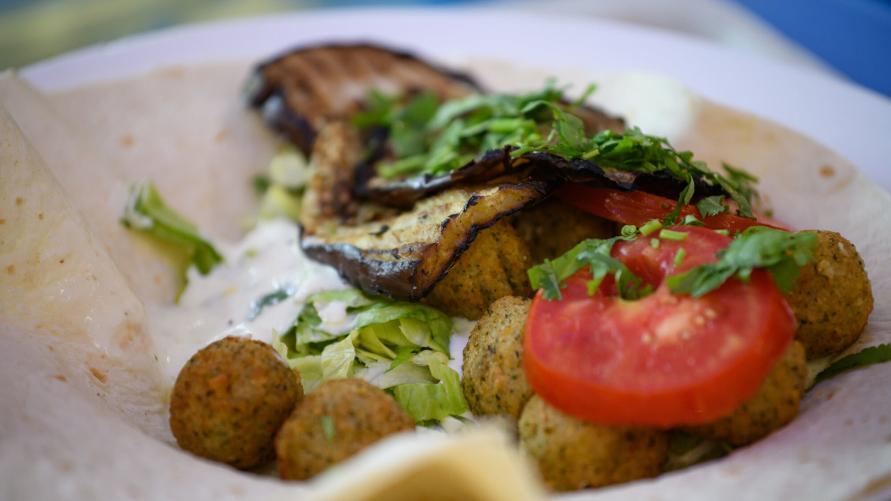 Ein Falafel-Wrap mit Salat, Auberginen, Tomaten und Petersilie.