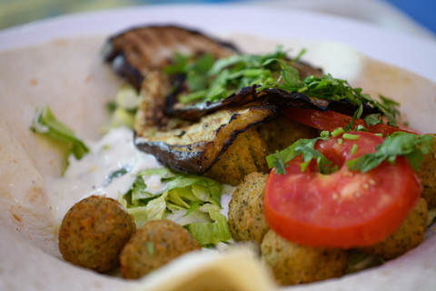Ein Falafel-Wrap mit Salat, Auberginen, Tomaten und Petersilie. 