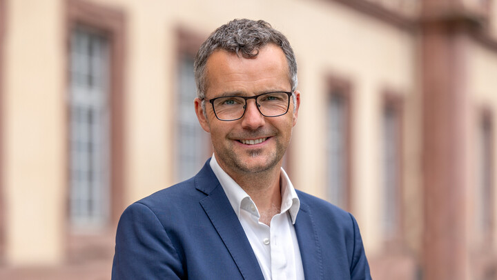 Porträtbild von Prof. Dr. Marc Debus vor dem Schloss