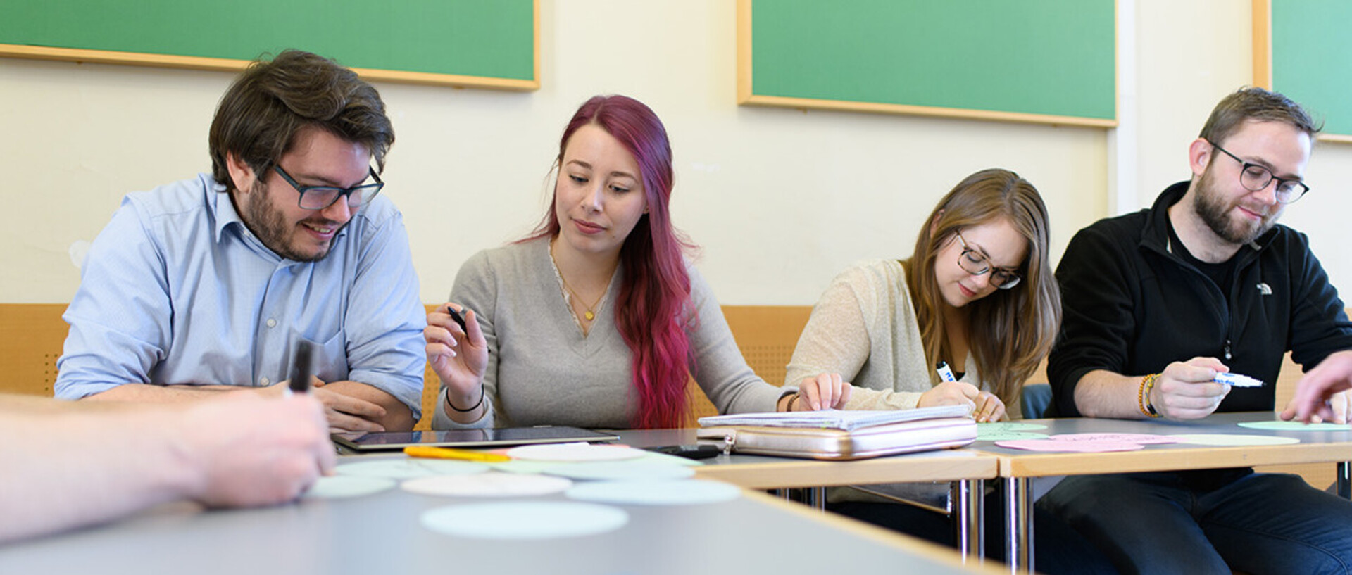 Studierende müssen Stichpunkte mit Filzstiften auf kleine Zettel schreiben.