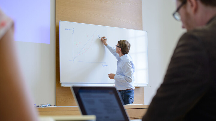 Ein Mann schreibt etwas auf ein Whiteboard.