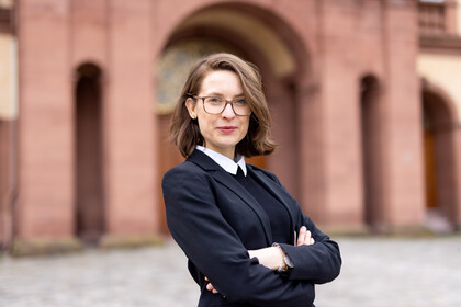 Prof. Svenja Behrendt hat die Arme vor der Brust verschränkt und steht vor dem Mannheimer Schloss. Sie trägt einen schwarzen Pullover.