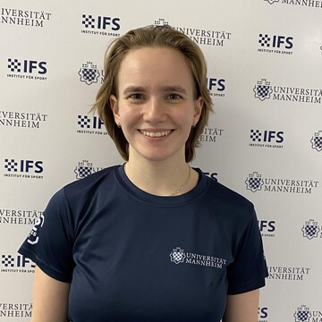 Hannah Koeppel hat lange braune Haare. Sie trägt ein dunkelblaues T-Shirt mit der Aufschrift "Universität Mannheim".