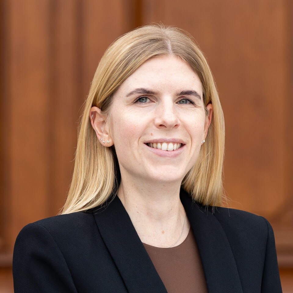 Laura Herzberg vor dem Schloss Mannheim. Sie trägt einen schwarzen Blazer und ein braunes Shirt.