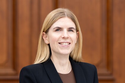 Laura Herzberg vor dem Schloss Mannheim. Sie trägt einen schwarzen Blazer und ein braunes Shirt.